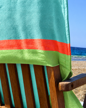 Close-up of the Mint & Lime 2-in-1 Beach Towel Bag on a wooden chair by the sea