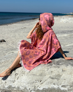Woman using a Towel to Go Hooded Cotton Beach Poncho in Camel and Rose from the Neon Safari on the beach 2.