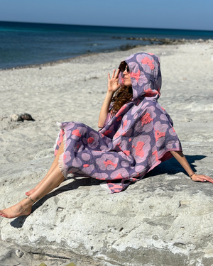 Woman using a Towel to Go Hooded Cotton Beach Poncho in Lavender and Coral from the Neon Safari on the beach 2.