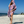 Woman using a Towel to Go Hooded Cotton Beach Poncho in Lavender and Coral from the Neon Safari on the beach.
