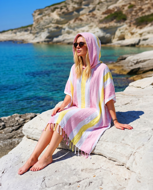 Woman using a Towel to Go Hooded Cotton Beach Poncho in Rose and Sunset from the Coral Coast on the beach.