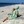 Woman using a Towel to Go Hooded Cotton Beach Poncho in Sage and Blush from the Neon Safari on the beach 2.